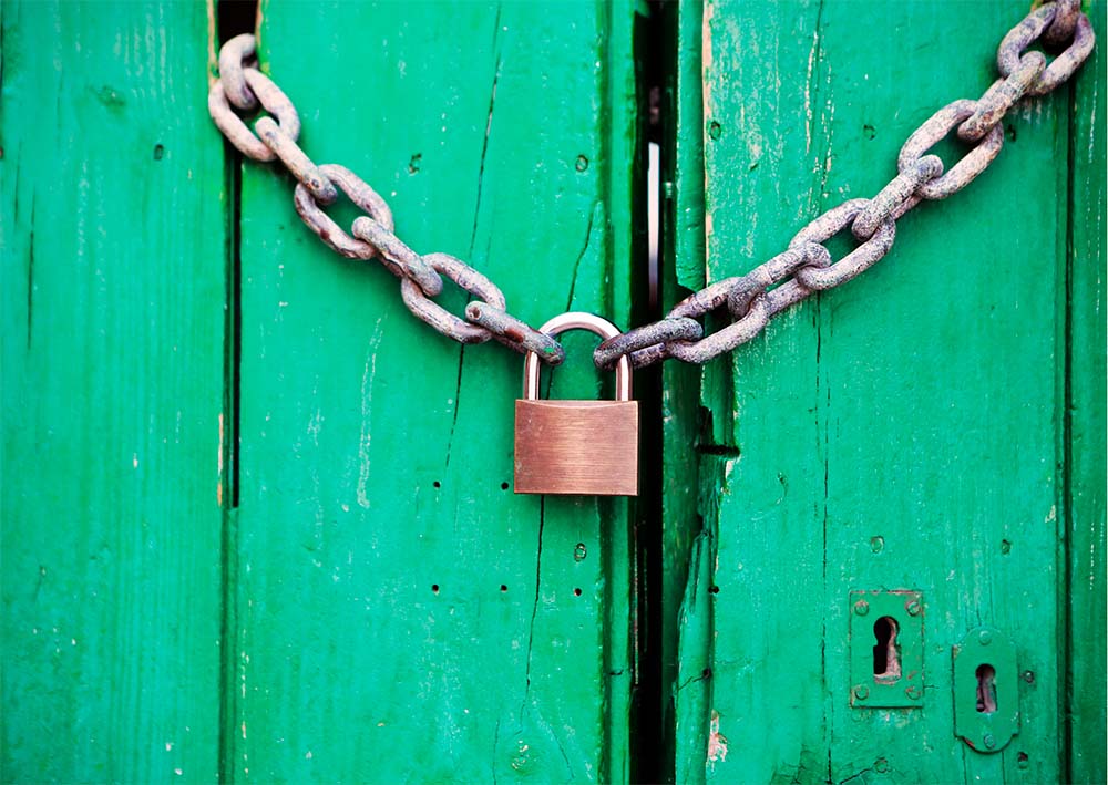 Bright green wooden door locked with chains and a padlock.